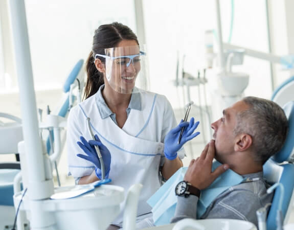 Dentist and dental patient talking to patient during oral cancer screening