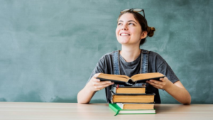 Teenager looking up from her books with chalkboard in the background